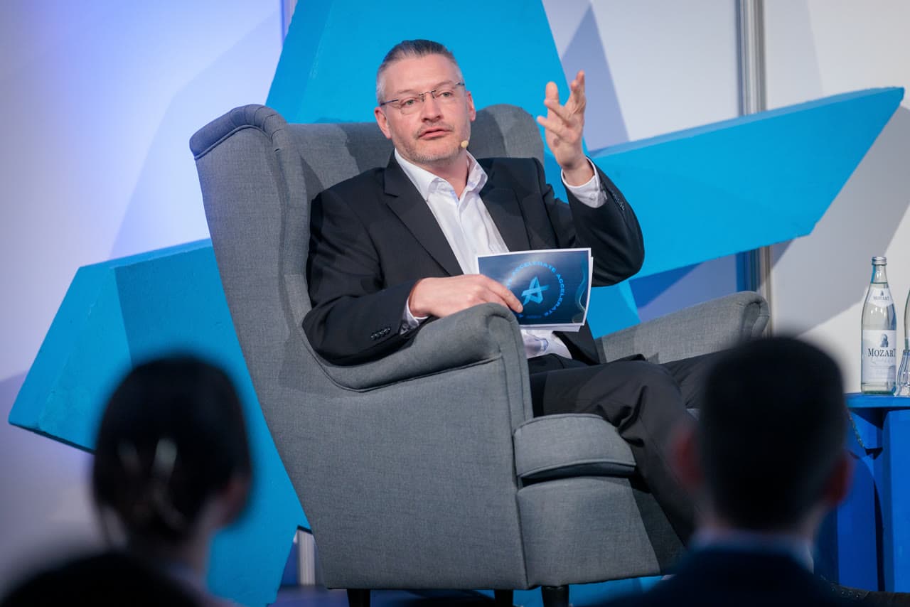 Dirk Brueckner seated on stage during a fireside conversation