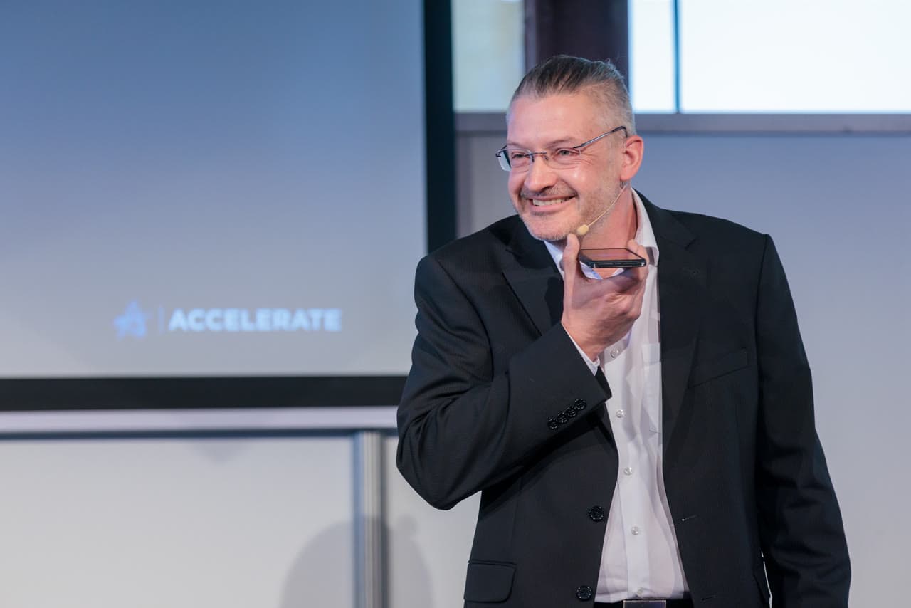 Dirk Brueckner smiling while speaking with a headset microphone
