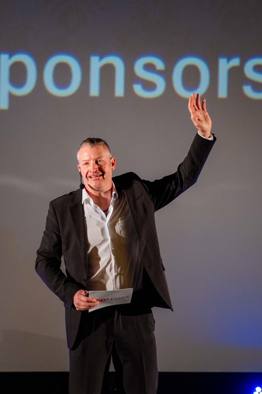 Dirk Brueckner greeting the audience from the TEDx Essen stage